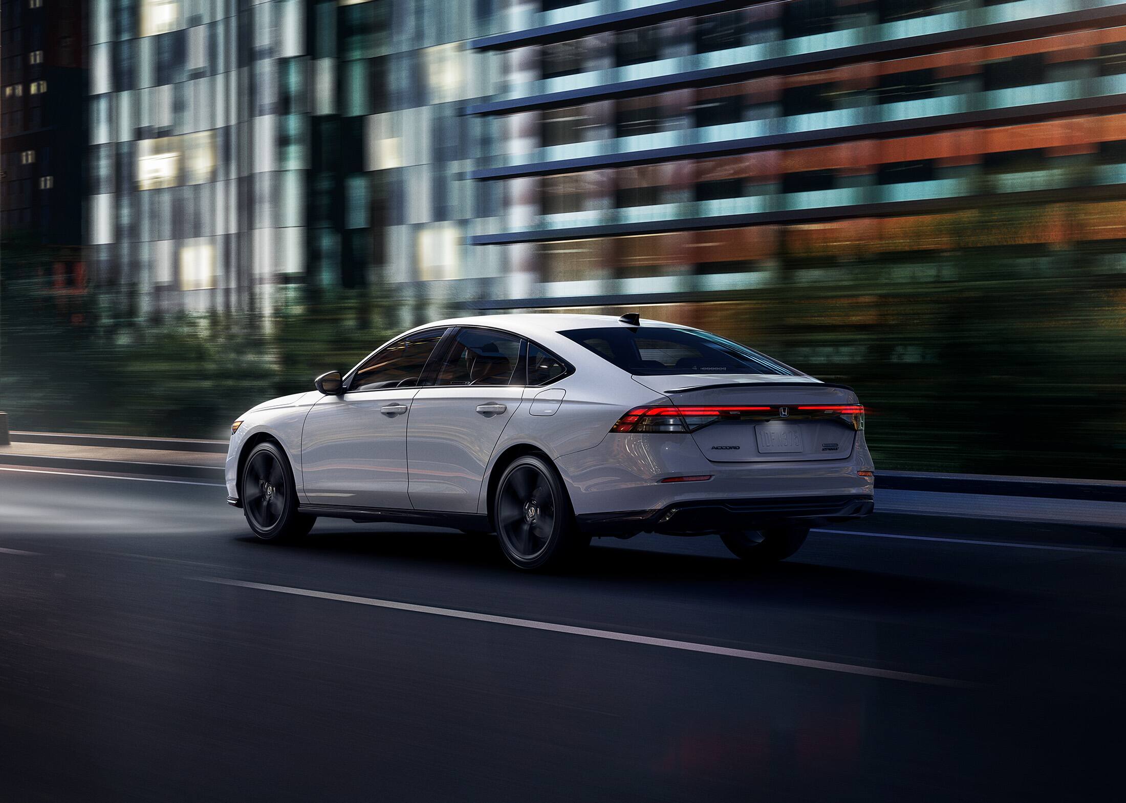 2026 Honda Accord 3/4 rear view in Platinum White Pearl driving in the city at night.